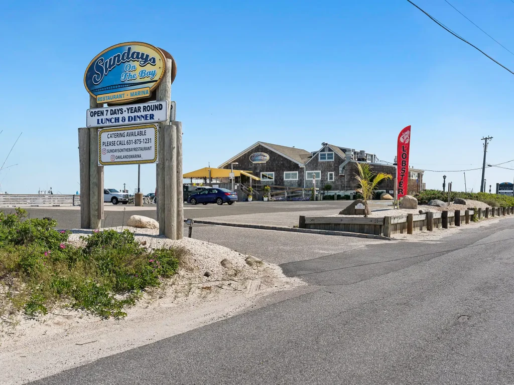 Coastal restaurant and marina with a large sign, a red "LOBSTER" flag, and a parking lot.